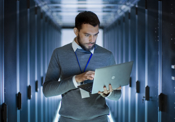 Man inside a server room using a laptop
